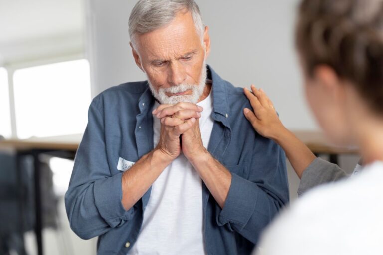 Homem cruza os dedos ao segurar queixo com expressão séria ao ouvir sobre tratamento do câncer de próstata