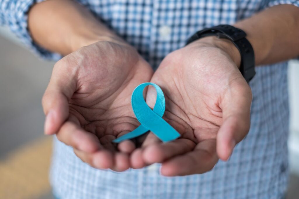 Homem segura laço azul que simboliza prevenção ao câncer de próstata