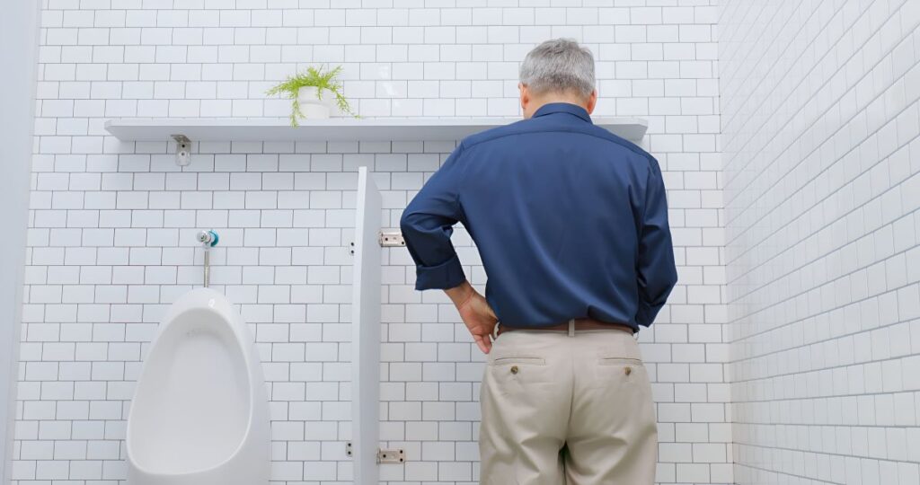 Homem com incontinência urinária em frente a mictório