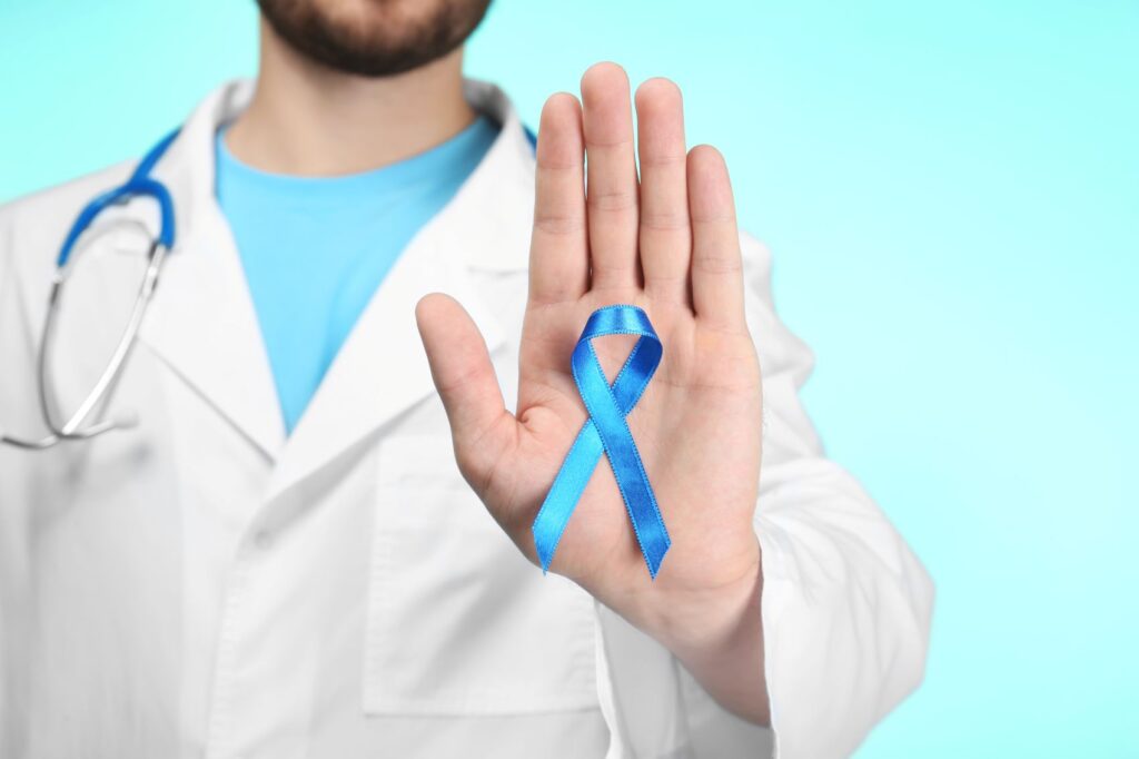 Médico com laço azul, alertando para a importância do diagnóstico precoce, em casos de câncer de próstata, metástase e sintomas.