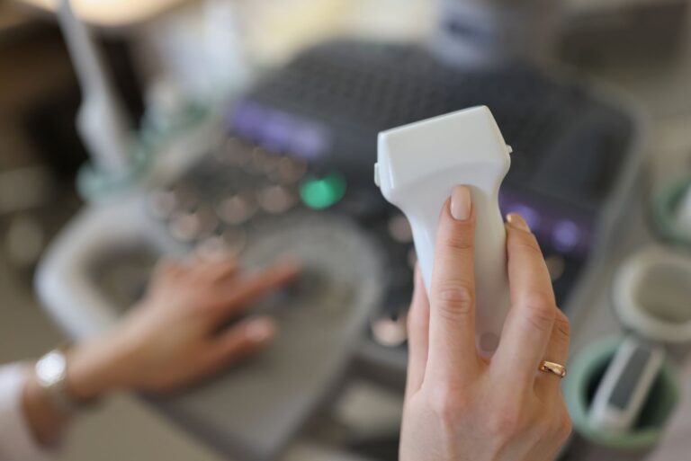 Médica segurando transdutor de ultrassom em ambiente clínico, representando exames preparatórios para cirurgia de próstata a laser.