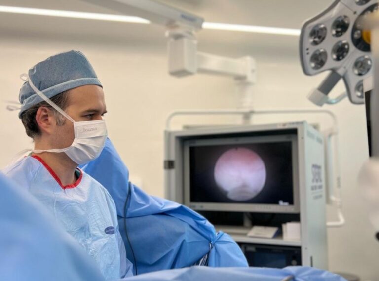 Dr José Vetorazzo durante cirurgia Holep em ambiente hospitalar, com monitor de exames ao fundo