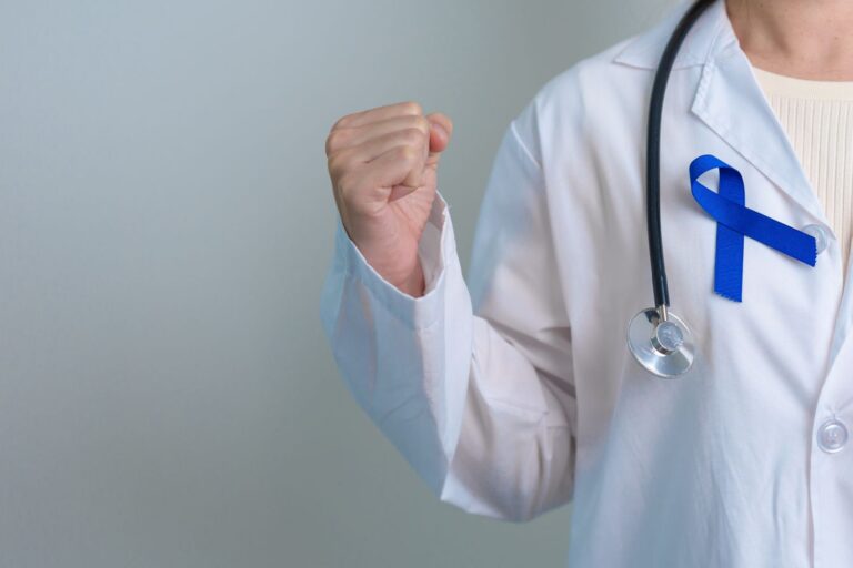 Médico urologista com laço azul no jaleco simbolizando conscientização e importância de entender o score de Gleason no câncer de próstata.