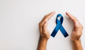 Mãos protegendo laço azul simbolizando vigilância ativa no câncer de próstata e acompanhamento médico regular.