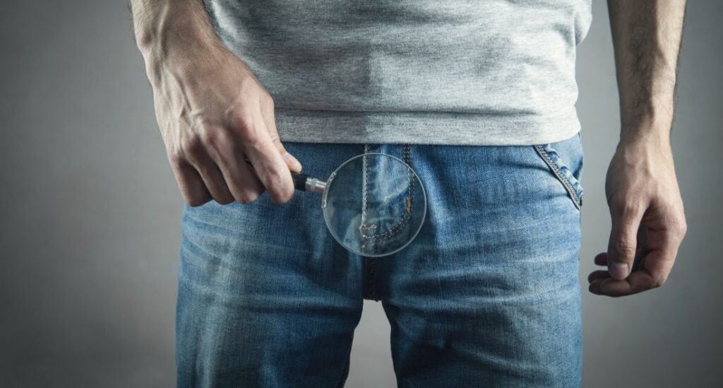 Homem com lupa na região genital ilustrando investigação detalhada da saúde masculina, associada à biópsia da próstata.