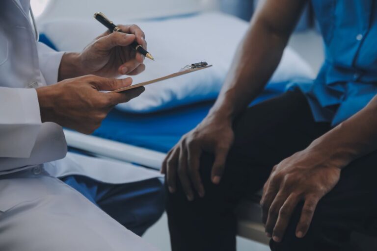 Médico registra informações durante consulta com paciente para discutir diagnóstico e tratamento, incluindo casos clínicos HoLEP e Rezum.