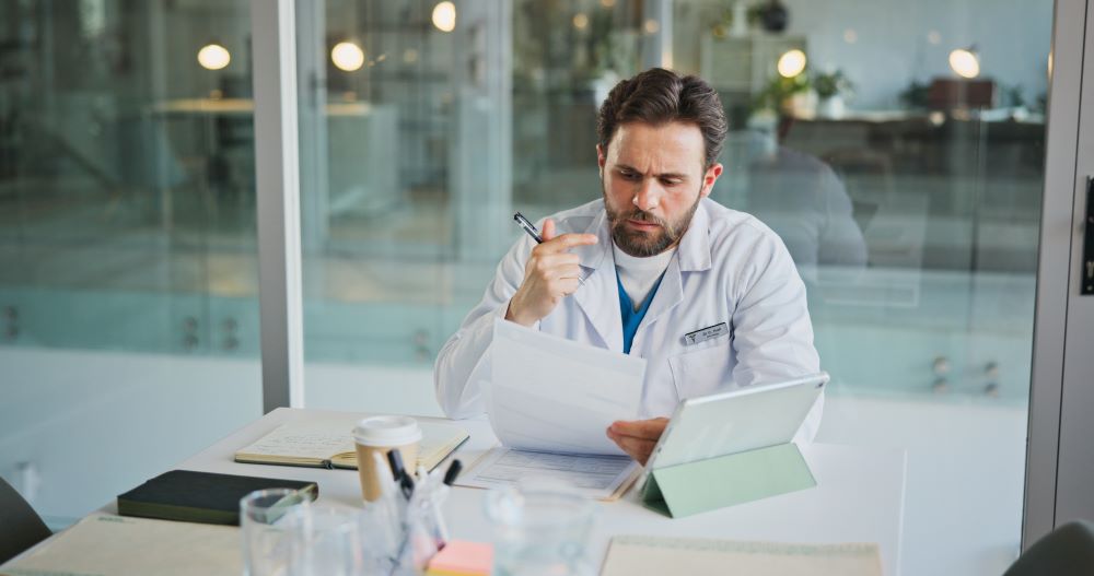 Médico analisa documentos e informações clínicas para avaliar opções de tratamento da próstata, incluindo HoLEP ou Rezum.
